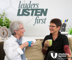 Two women talking on a couch holding coffee cups