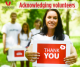 YOung woman with dark hair holding as thank you sign to acknowledge volunteers. three people in the background with volunteer on white t shirts