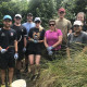 A team of volunteers from KPMG, standing with shovels, among the plants at Oakley Creek