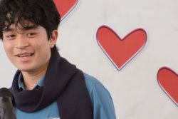 Sora Endo wearing a blue shirt, speaking at the Annual Love Awards 2022. Background of red hearts on white board